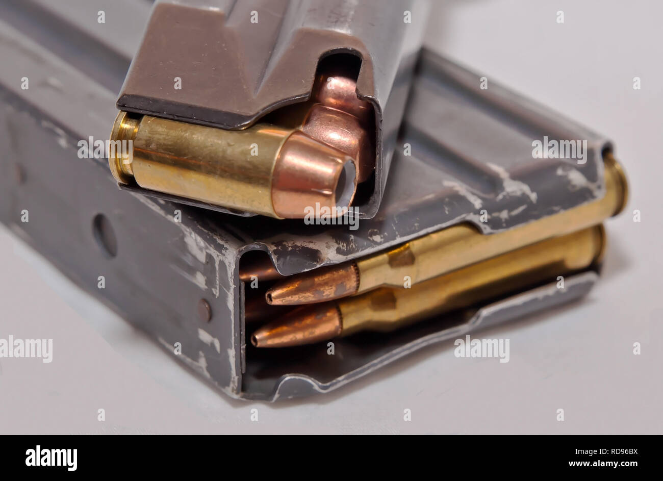 Una rivista revolver caricato con .40 calibro punto cava proiettili sulla parte superiore di una rivista di fucile caricato con calibro .223 elenchi puntati su sfondo bianco Foto Stock