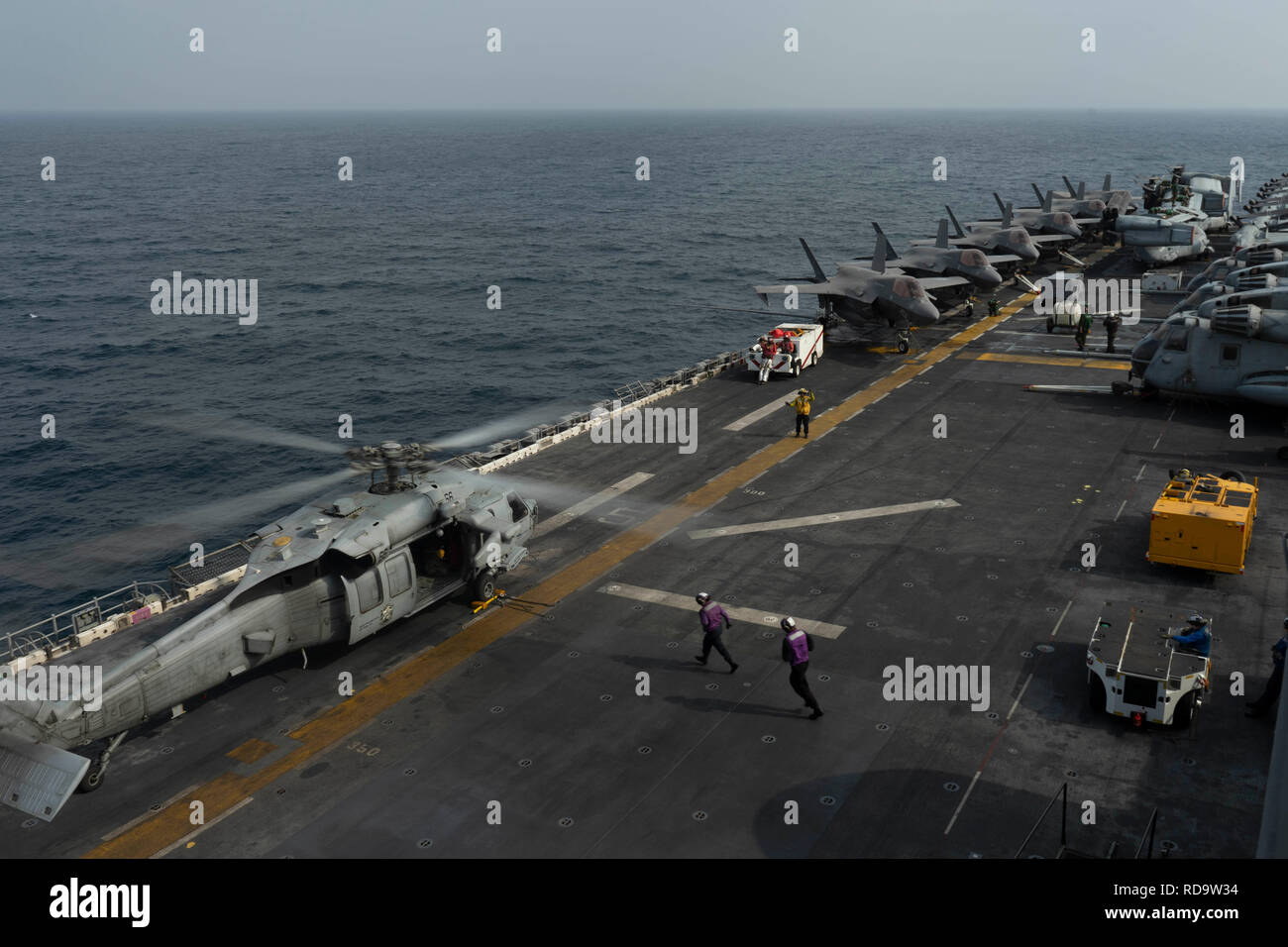 Mare Arabico (GEN. 14, 2019) marinai esegui per rifornire un MH-60S Sea Hawk elicottero, assegnato al "blackjack" di elicottero di mare squadrone di combattimento (HSC) 21, sul ponte di volo di wasp-classe assalto anfibio nave USS Essex (LHD 2) durante una distribuzione di Essex anfibio gruppo pronto (ARG) e xiii Marine Expeditionary Unit (MEU). L'Essex ARG e xiii MEU è un flessibile e persistente Navy-Marine Corps team distribuito negli Stati Uniti Quinta Flotta area di operazione a sostegno di operazioni navali per garantire stabilità marittimo e la sicurezza nella regione centrale di collegamento del Mediterraneo e del Pacifi Foto Stock