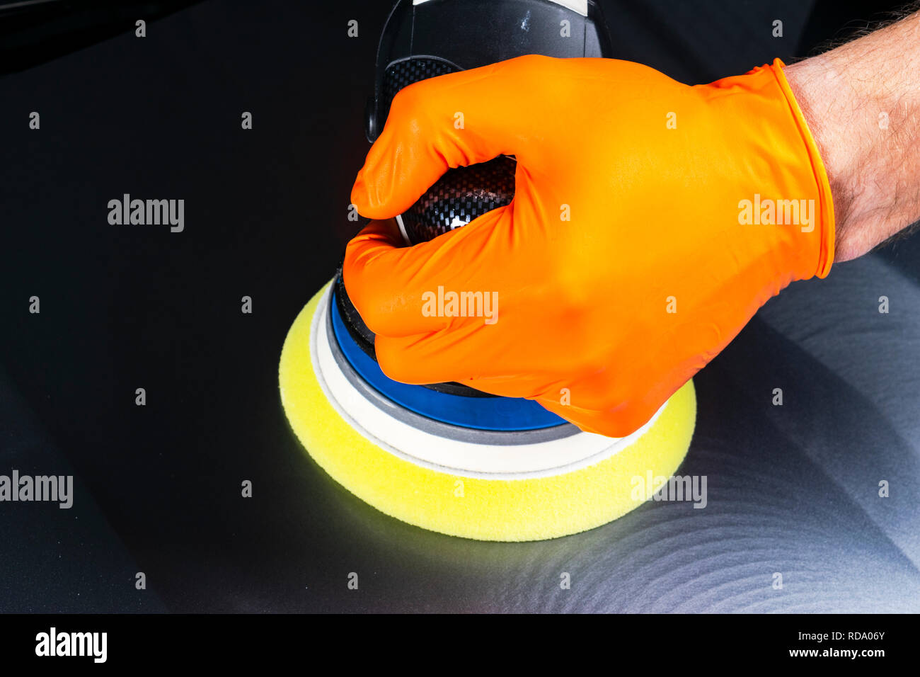 Auto cera polacco lavoratore mani applicando il nastro protettivo prima della lucidatura. Pulitura e lucidatura auto. Dettagli auto. Chi detiene un lucidante in mano e Foto Stock