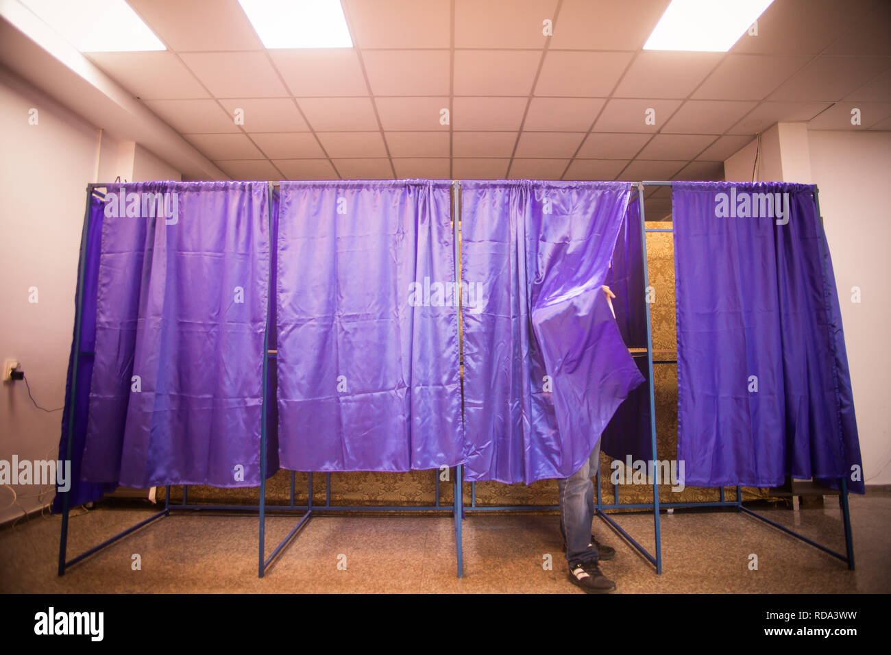 Immagine a colori di una persona non identificabili voto in capanne in corrispondenza di una stazione di polling, durante le elezioni. Foto Stock