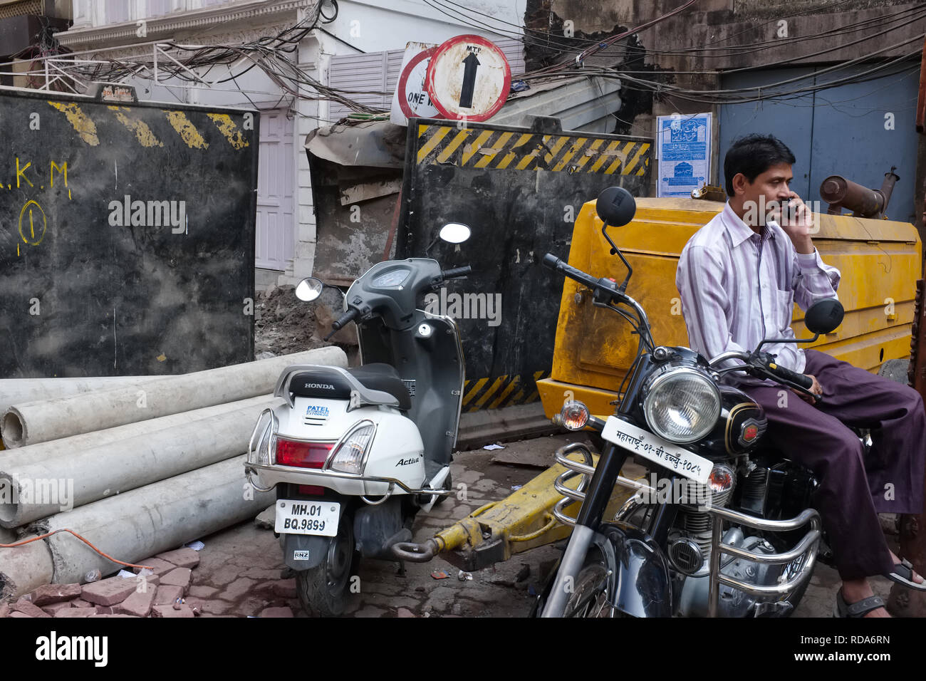 Un uomo parla sul suo telefono cellulare in un fatiscente in corsia Bhendi area Bazaar di Mumbai, India Foto Stock