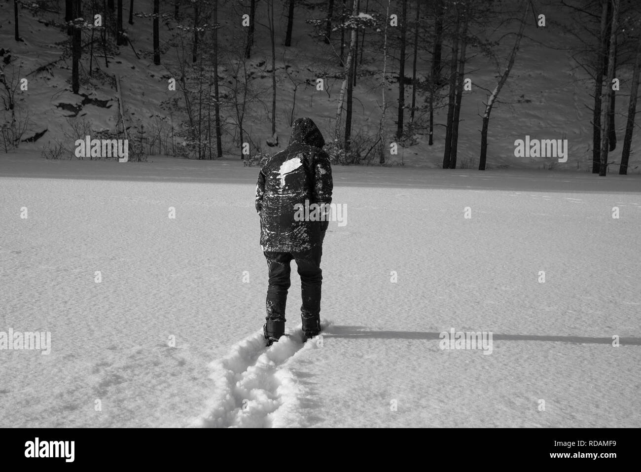 Un uomo a camminare nella neve. in bianco e nero Foto Stock