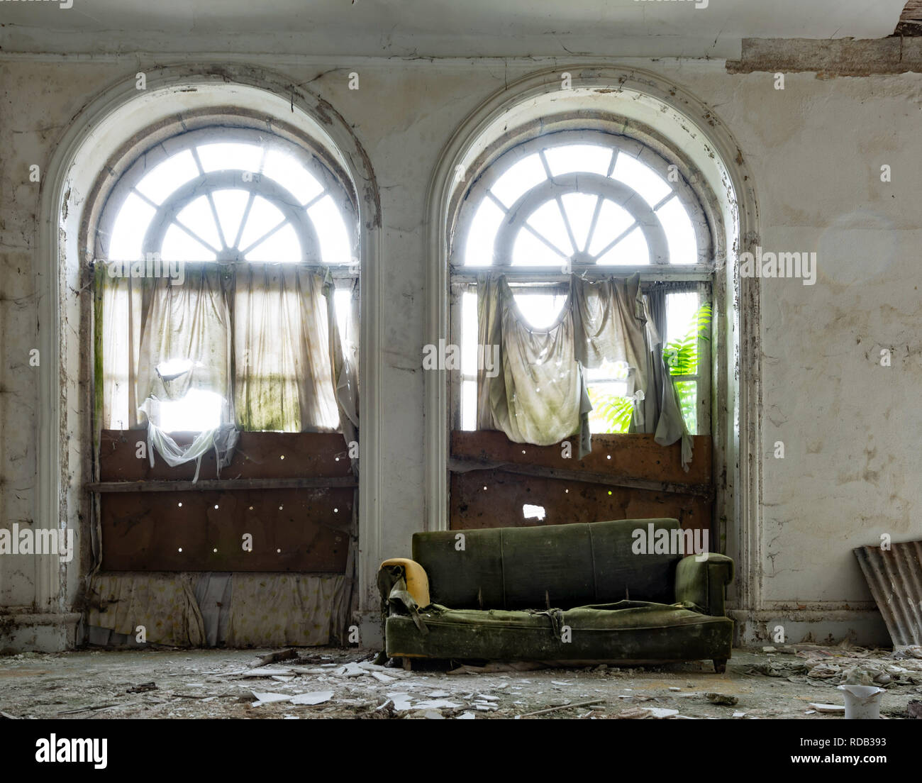 Un vecchio divano letto in una stanza distrutta con splendidi telai di finestra Foto Stock