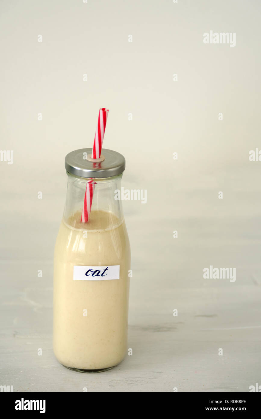 Bottiglia di vetro di latte di avena su sfondo bianco. Foto Stock