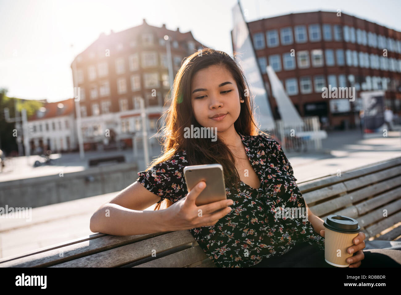 Giovani asiatici studente di college udienza del campus tramite il suo cellulare Foto Stock