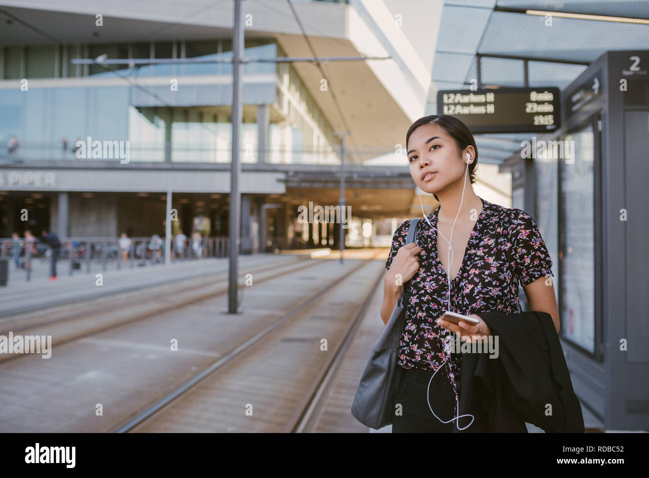 Imprenditrice asiatici in attesa di un tram durante i suoi spostamenti di mattina Foto Stock
