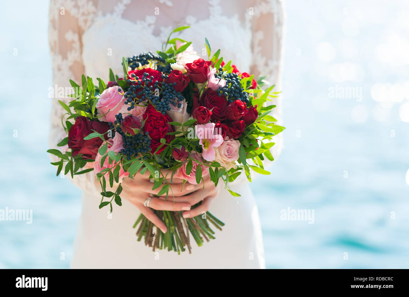Luminose wedding bouquet di rose e bacche di sambuco detenute nelle mani della sposa Foto Stock