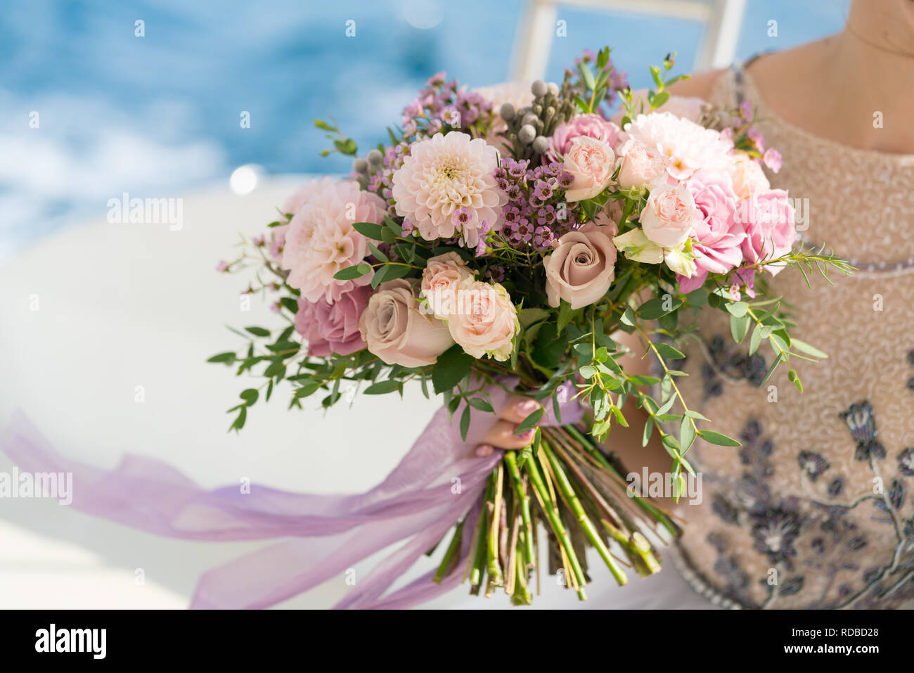 La sposa detiene una rosa e lilla Bouquet nozze nelle sue braccia contro lo sfondo del mare Foto Stock