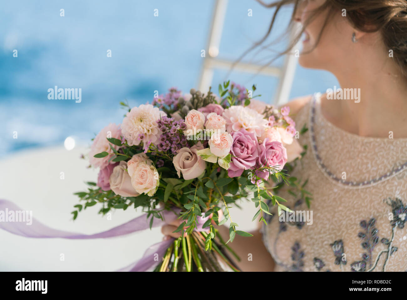La sposa detiene una rosa e lilla Bouquet nozze nelle sue braccia contro lo sfondo del mare Foto Stock