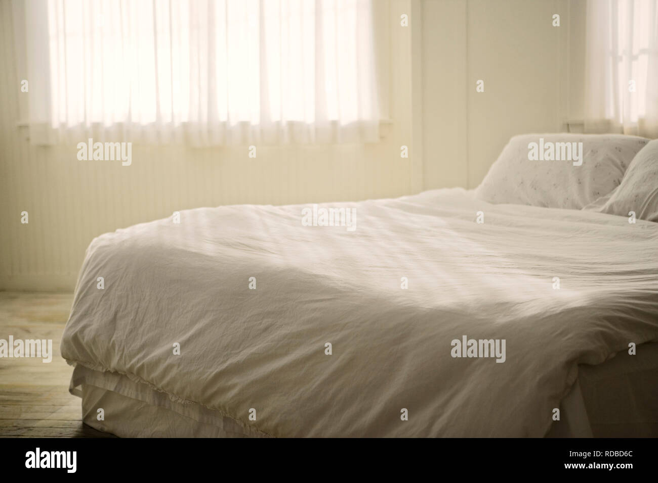 Lenzuola bianche su un letto all'interno di una camera bianca. Foto Stock