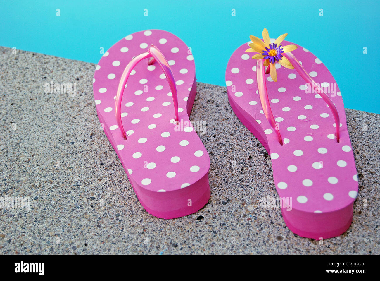 Coppia di colore rosa e bianco polka dot flip-flop a bordo piscina. Foto Stock
