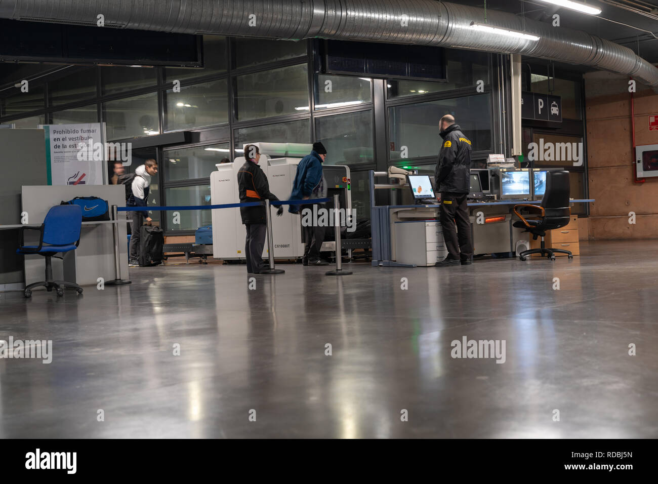 I viaggiatori passando il controllo di sicurezza con una macchina a raggi X, sotto la supervisione del personale di sicurezza nella stazione ferroviaria per treni ad alta velocità di Guadalajara Yebe Foto Stock