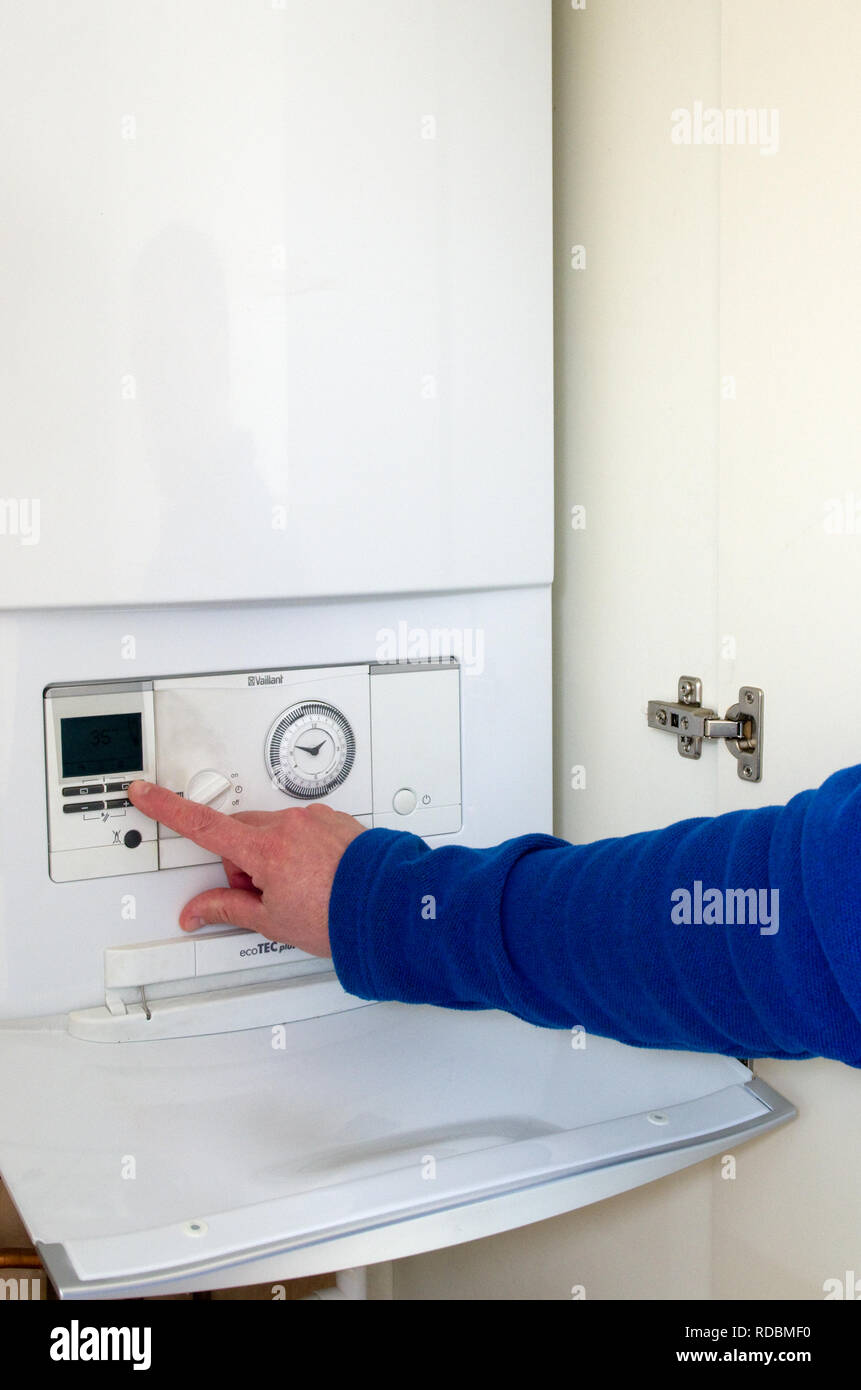 Uomo caucasico Regolazione o impostazione orologio su una Vaillant Combinazione di riscaldamento centralizzato a gas caldaia, REGNO UNITO Foto Stock
