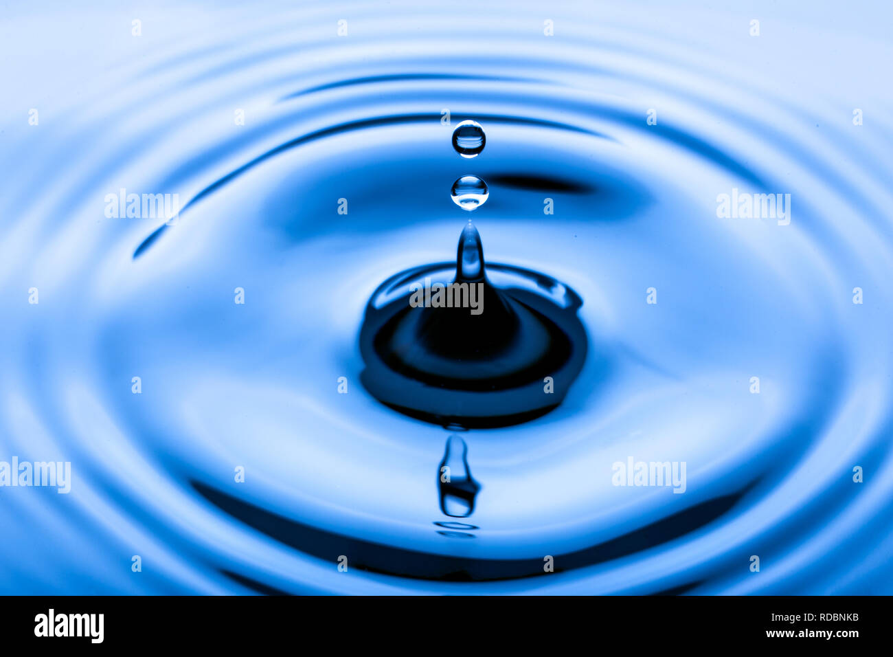 Blu le goccioline di acqua che rientrano nell'acqua Foto Stock