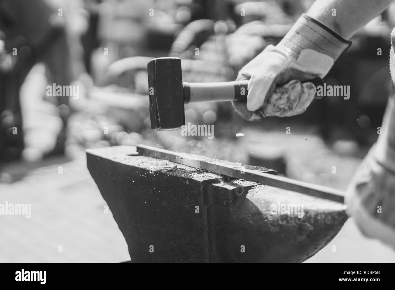 Un fabbro di martellatura a caldo di un asta di metallo a forma di esso. Foto Stock