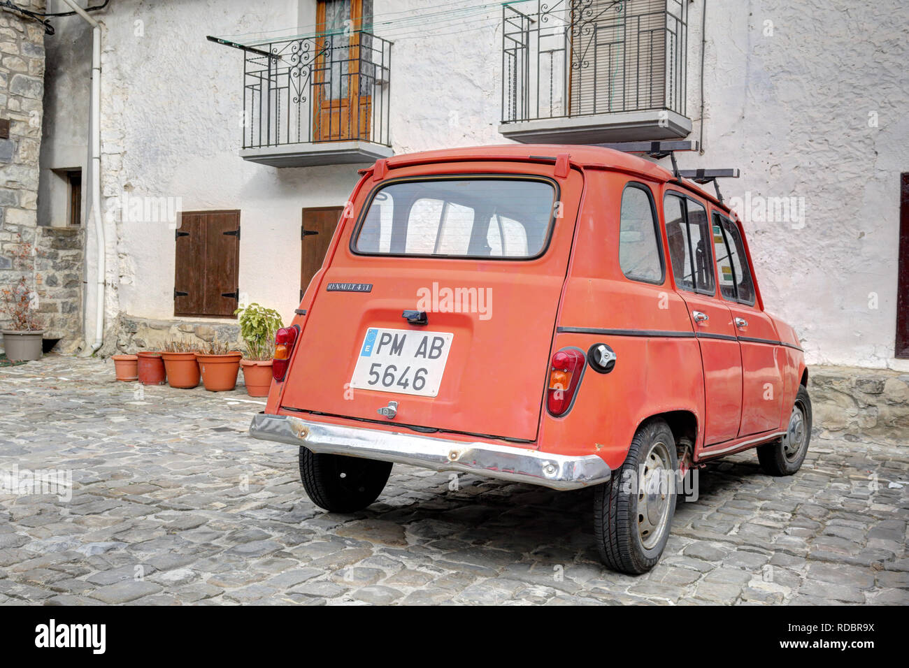 Un tradizionale vecchio Renault 4 TL red auto parcheggiate nella piazza di pietra del mondo rurale città di montagna di Ansó, nei Pirenei Aragonesi Foto Stock