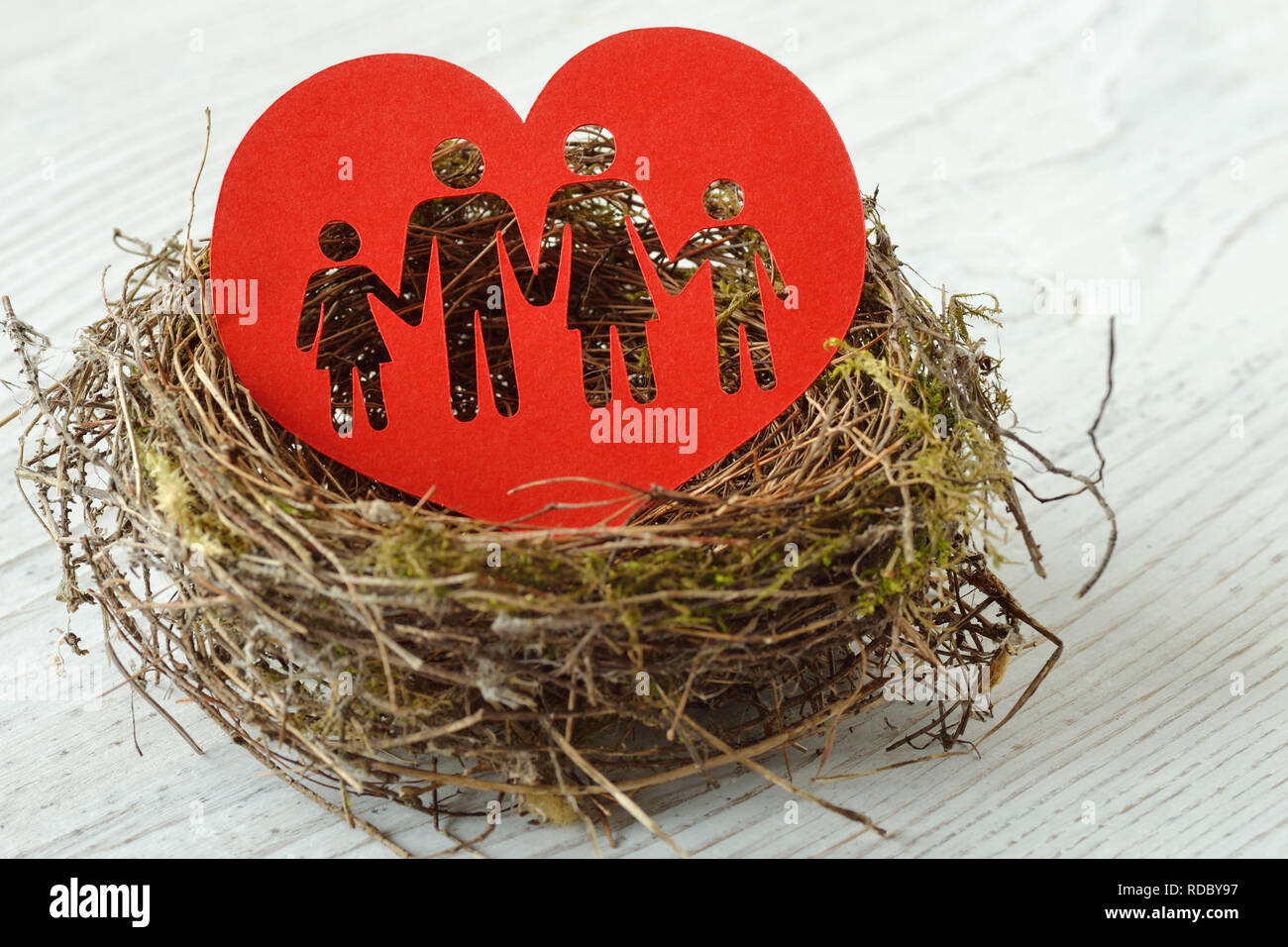 Famiglia silhouette ritagliata nel cuore di carta in un nido - Concetto di amore e famiglia Foto Stock