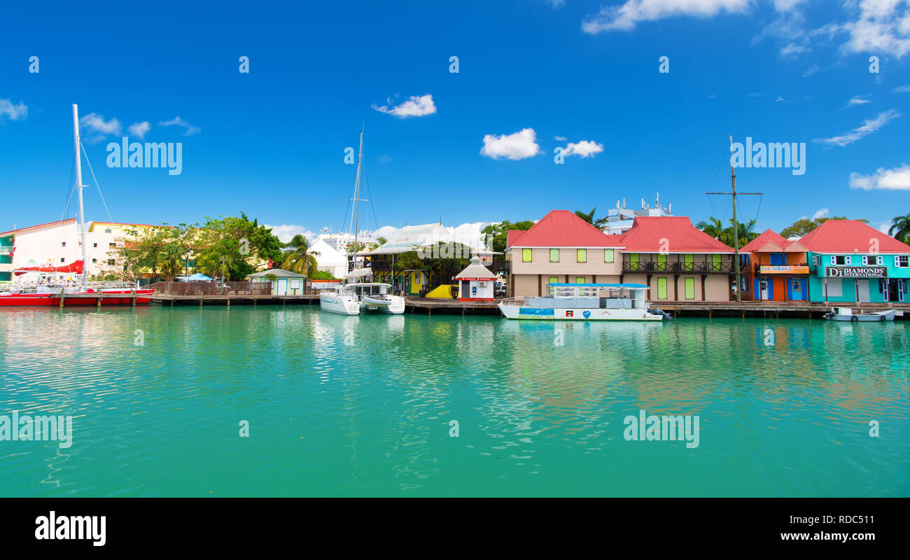 St Johns, Antigua - Marzo 05, 2016: quay con case e barche in mare turchese sul cielo blu. Viaggiare e wanderlust. Vacanze estive sull isola tropicale. Foto Stock