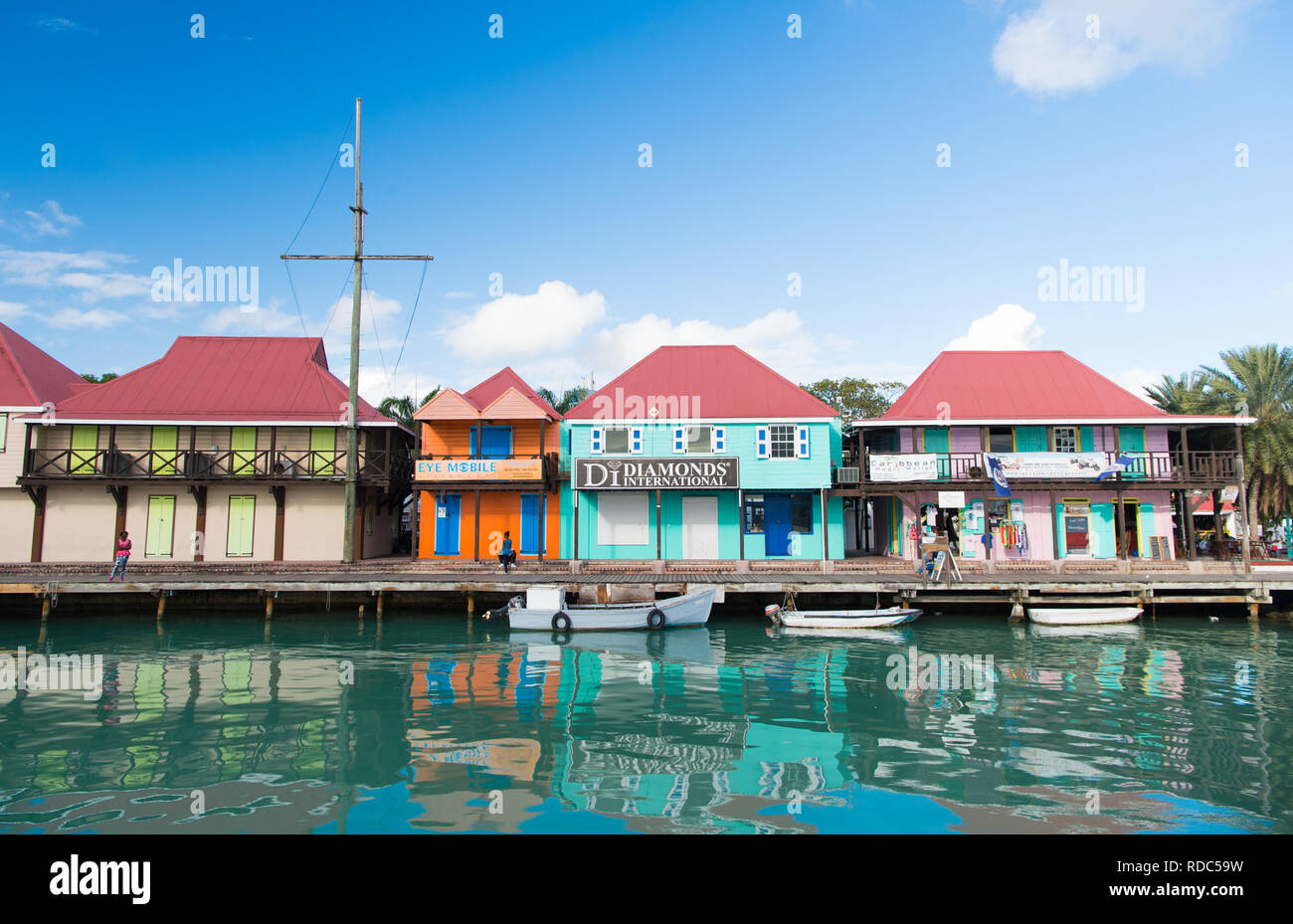 St Johns, Antigua - Marzo 05, 2016: barche ormeggiate in mare al molo del villaggio con case a cielo blu. Vacanze estive sull isola tropicale. La scoperta e l'avventura. Wanderlust. Foto Stock
