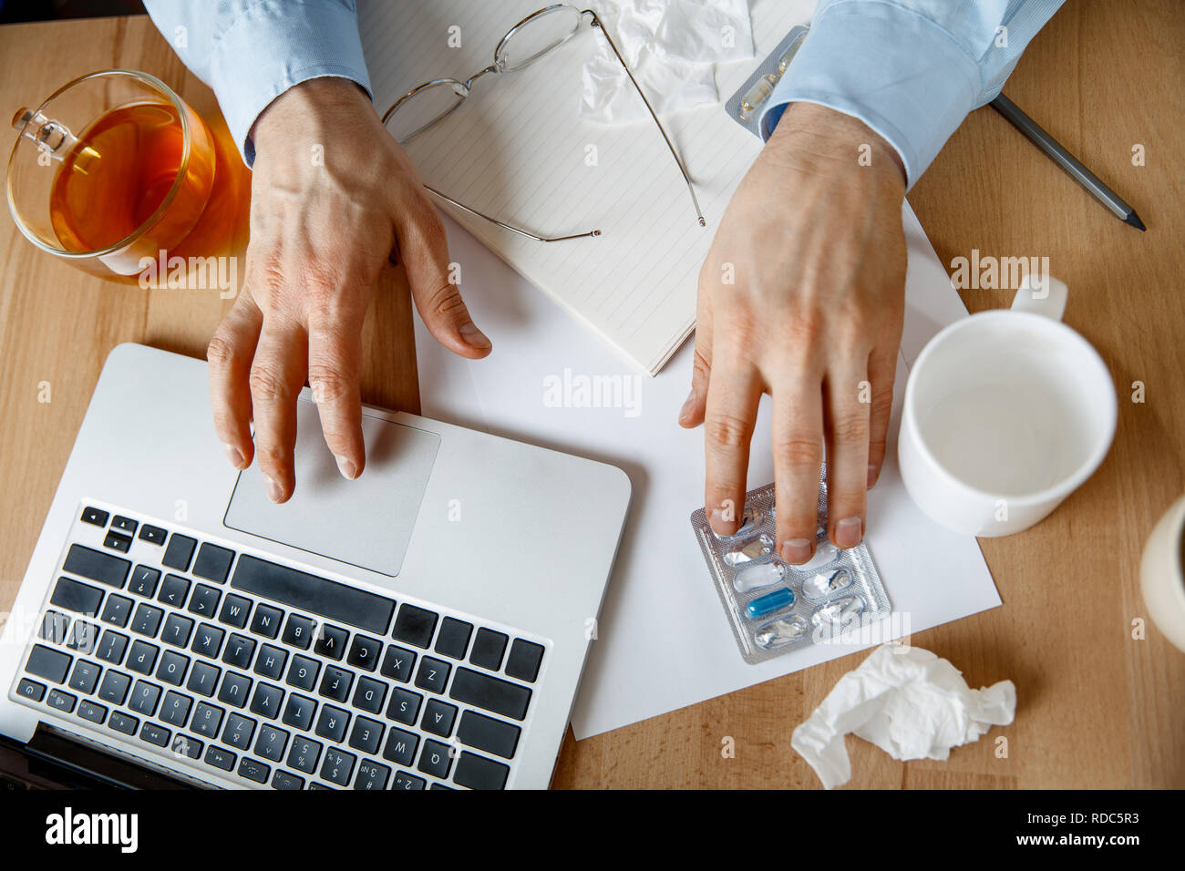 Uomo malato con le pillole che lavorano in ufficio, imprenditore catturati freddo, l'influenza stagionale. Pandemia di influenza, la prevenzione delle malattie, la malattia, virus, infezione, temperatura, febbre e concetto di influenza Foto Stock
