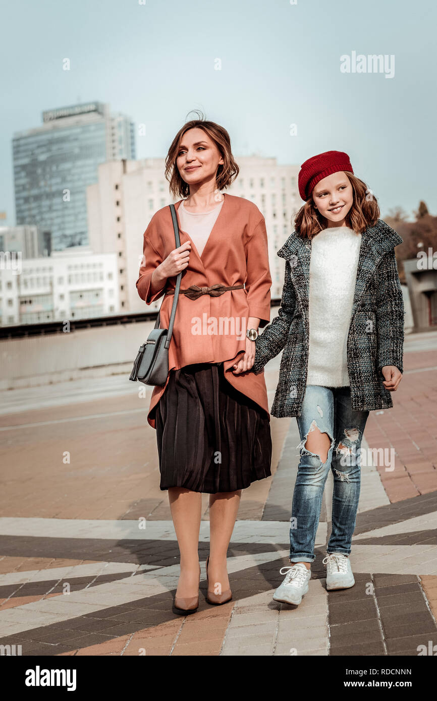 Ragazza indossando berretto rosso a piedi con sua madre Foto Stock