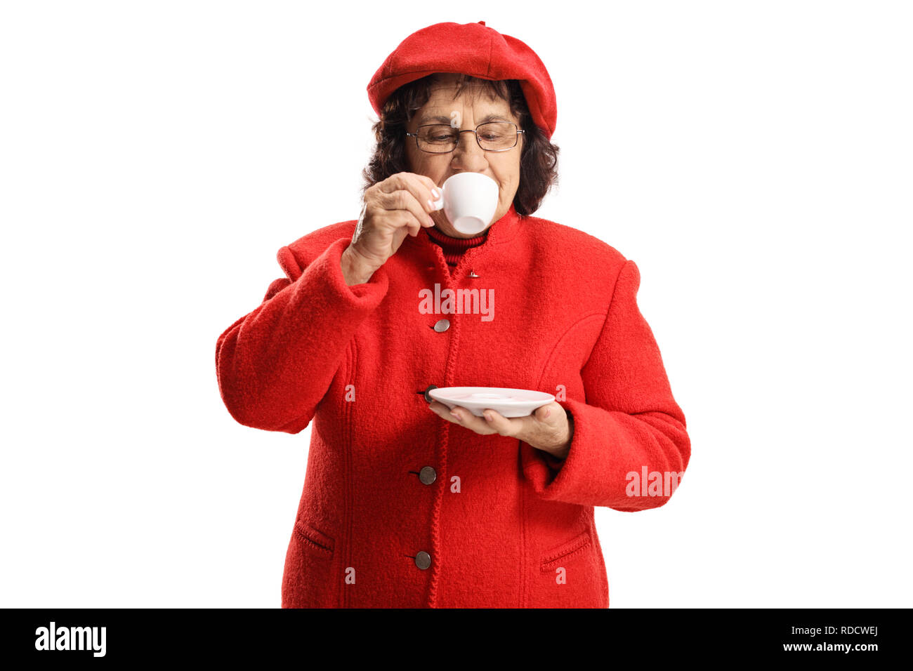 Signora anziana in un cappotto rosso prendendo un sorso di caffè espresso isolati su sfondo bianco Foto Stock