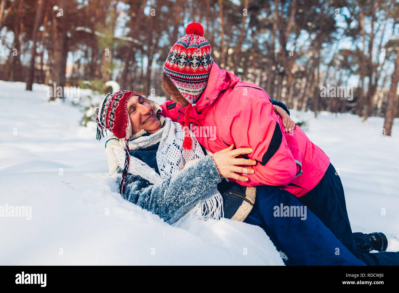 Coppia senior abbracciando nella foresta d'inverno. L uomo e la donna che giace nella neve e divertimento nel giorno di San Valentino in esterno Foto Stock