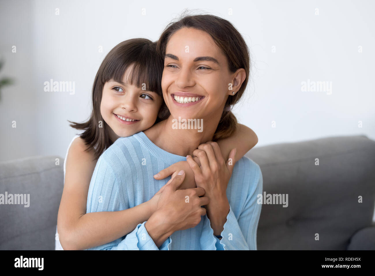 Mom sorridente e graziosa figlia di capretto abbracciando cercando in futuro Foto Stock