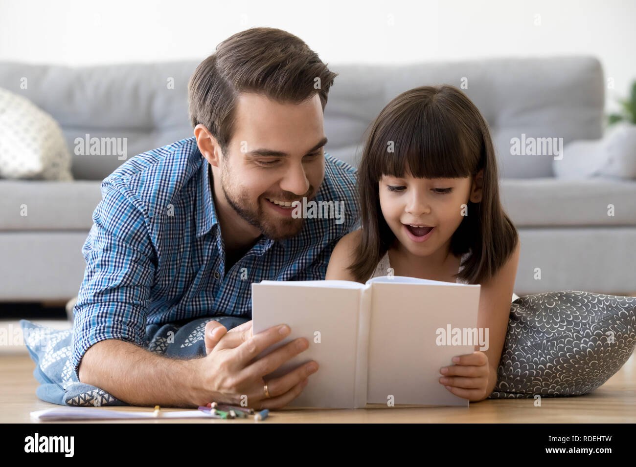 Padre Felice e sorpreso kid lettura della ragazza prenota insieme Foto Stock