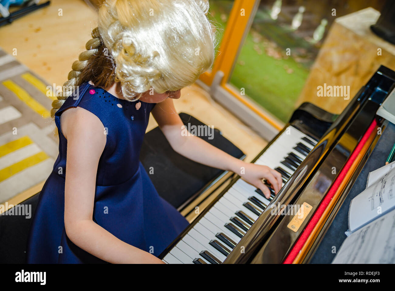 Carino bambina suonare il pianoforte, dressing rétro Mozart periwig, interni Foto Stock