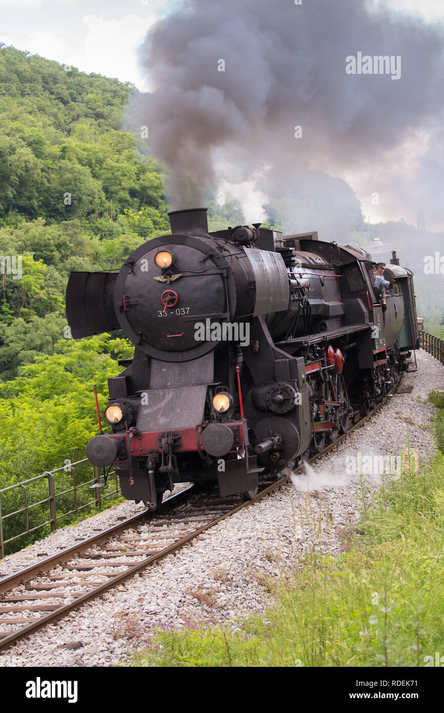 Il vecchio treno a vapore attraversando il ponte di Solkan a Nova Gorica, in Slovenia, l'Europa. Un sacco di nero e grigio vapore nascondendo la locomotiva, frame completo Foto Stock