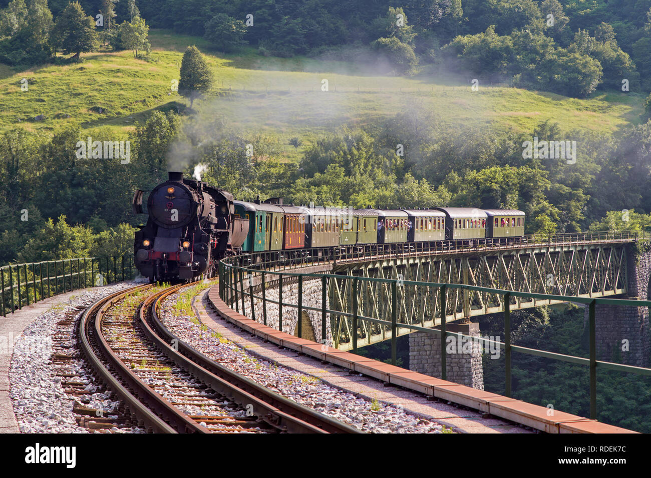 Il vecchio treno a vapore attraversando il ponte di Solkan a Nova Gorica, in Slovenia, l'Europa. Un sacco di nero e grigio vapore nascondendo la locomotiva, frame completo Foto Stock
