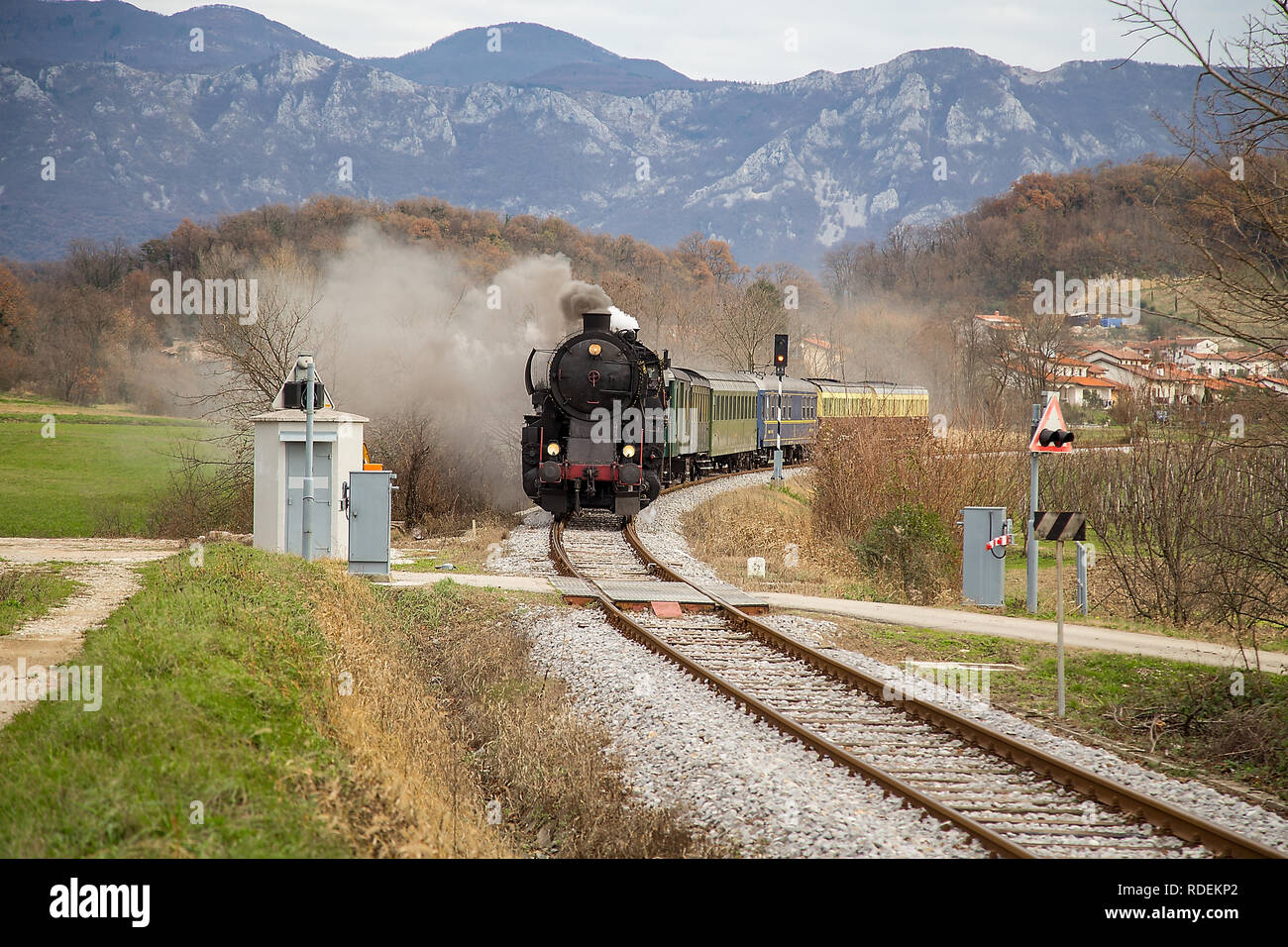 Il vecchio treno a vapore lasciando la stazione ferroviaria di Ajdovščina, Slovenia, l'Europa. Un sacco di nero e grigio vapore nascondendo la locomotiva, frame completo Foto Stock