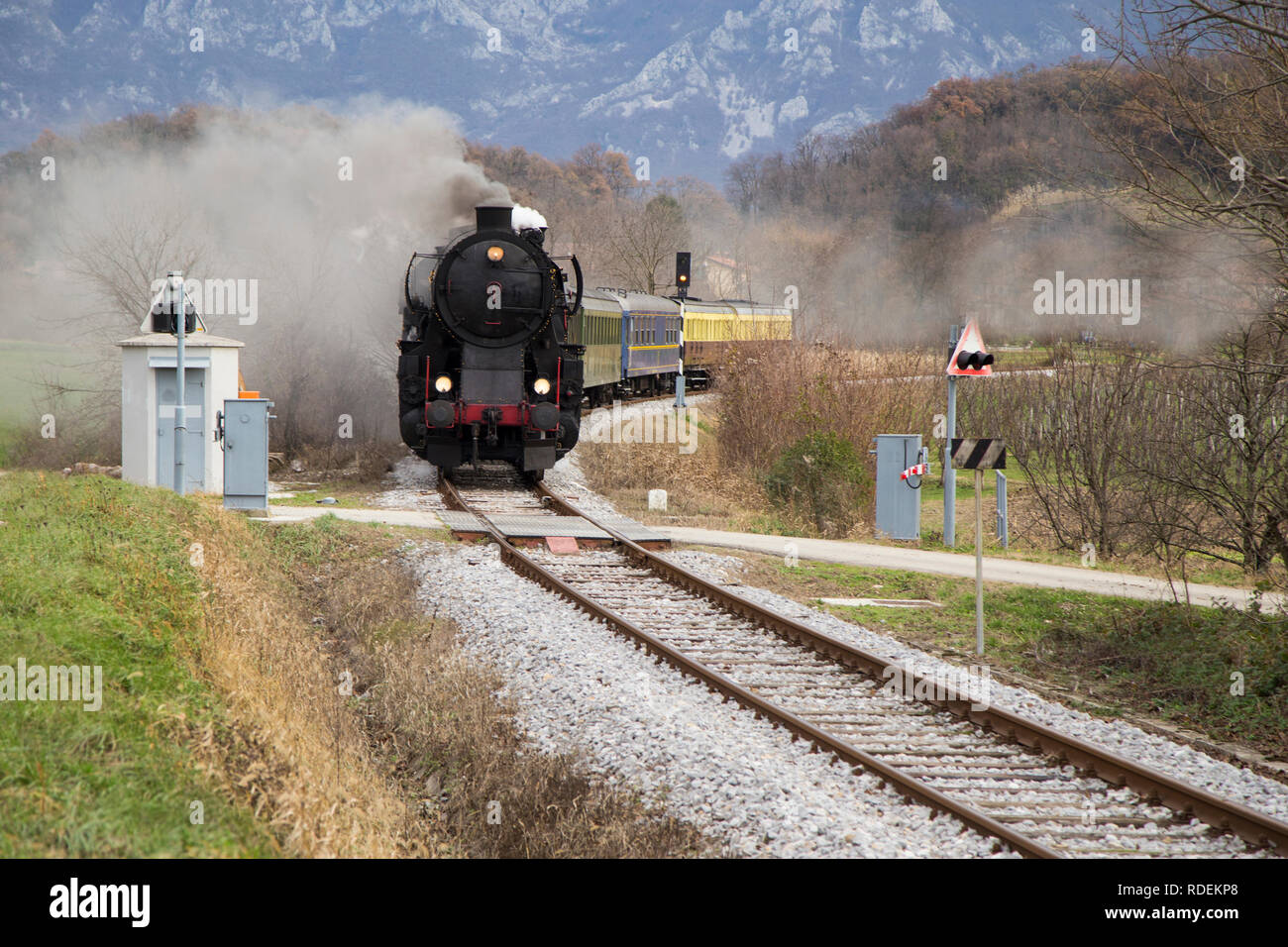 Il vecchio treno a vapore lasciando la stazione ferroviaria di Ajdovščina, Slovenia, l'Europa. Un sacco di nero e grigio vapore nascondendo la locomotiva, frame completo Foto Stock