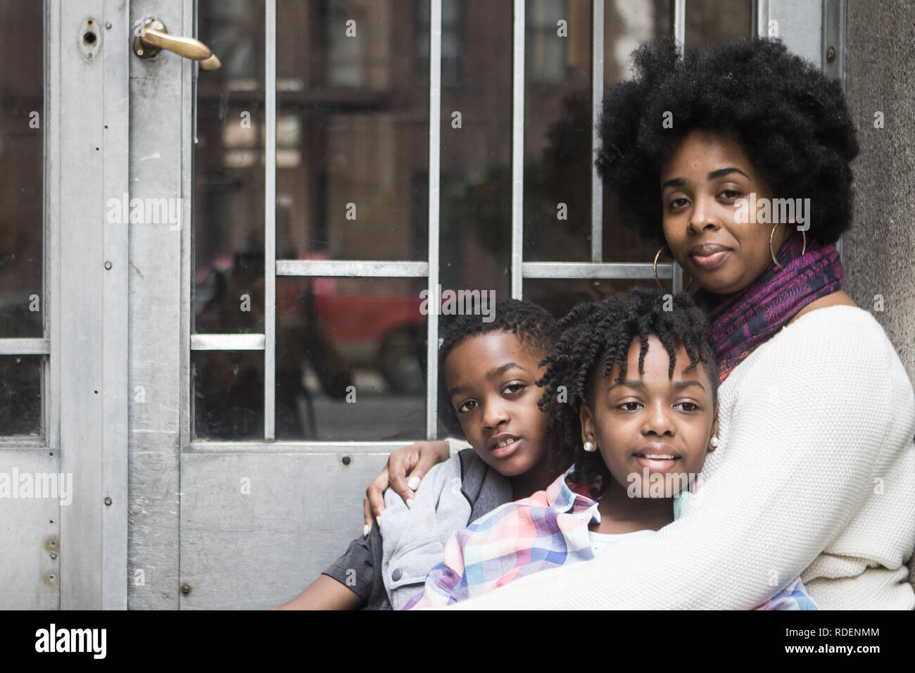 African American madre con bambini seduti fuori sorridente Foto Stock