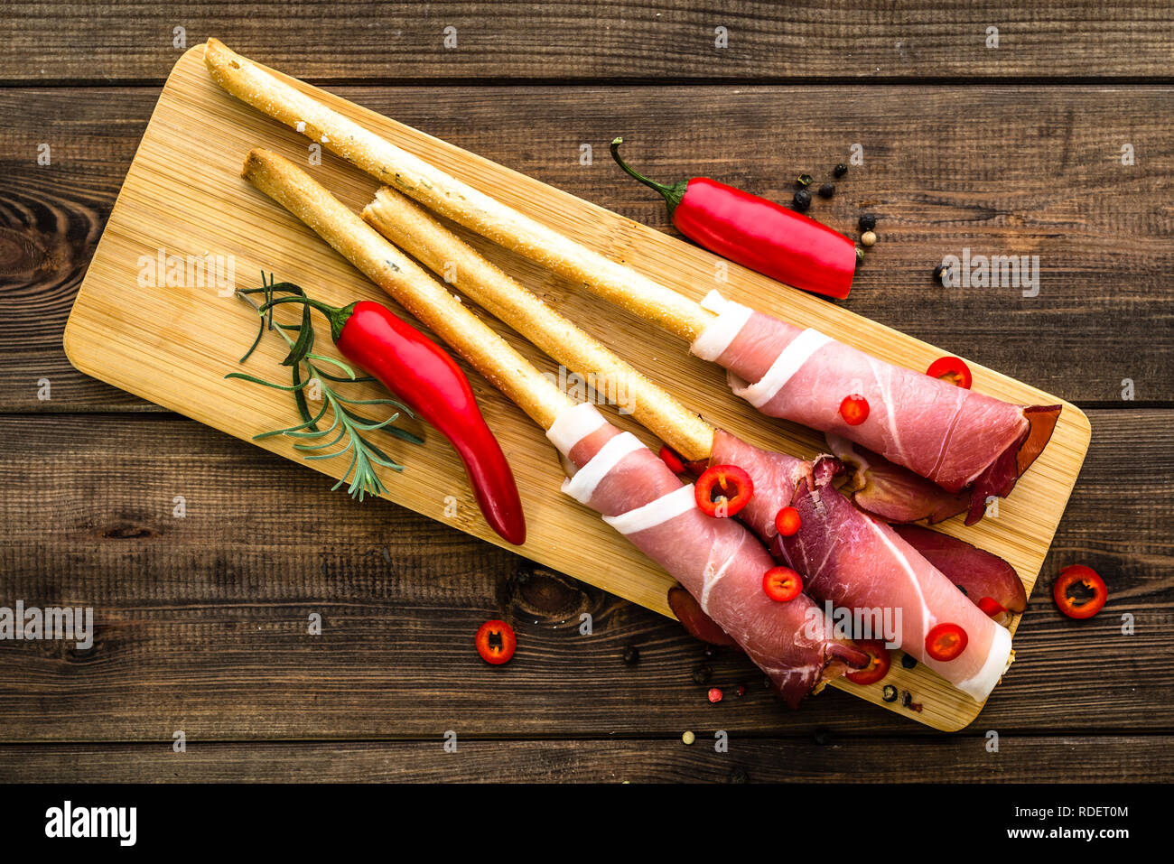 Stick di pane con prosciutto, italiano tradizionale di antipasti, piatti sul tavolo di legno, overhead Foto Stock