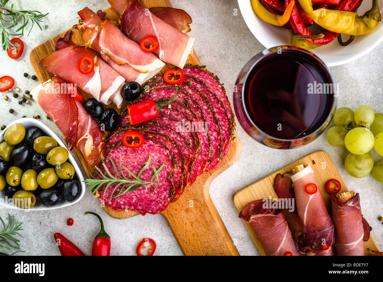 Tipici antipasti all'italiana, prosciutto e salame sul piatto da portata, la selezione di cibo sul tavolo con bicchiere di vino, vista dall'alto Foto Stock