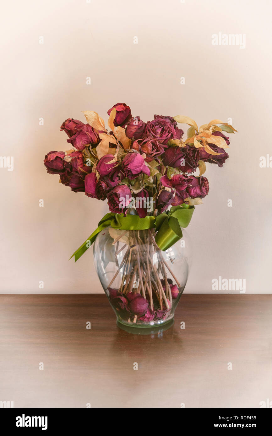 Essiccato rose rosse fiori in un vaso di vetro con il nastro verde Foto Stock