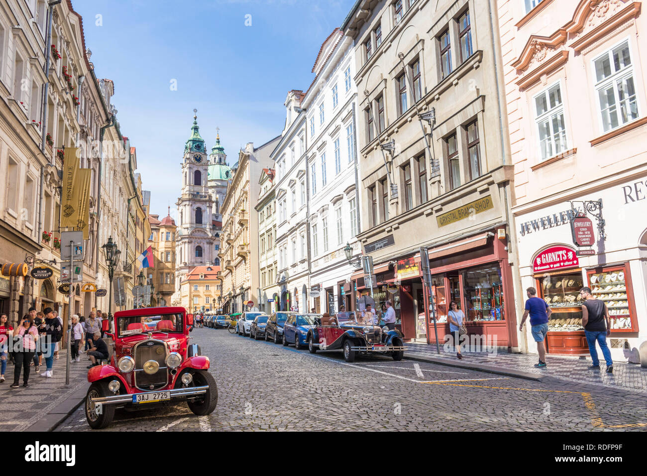 I turisti di Praga e di visite e automobili parcheggiate su Mostecka con la Chiesa di San Nicola Kostel sv. Mikuláše Mala Stana Praga Repubblica Ceca Europa Foto Stock