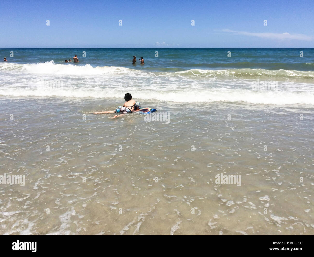 Ragazzo giocando sulla spiaggia, da soli (bambino giacente in acqua da sola) - Cocoa Beach, Florida, Stati Uniti d'America Foto Stock