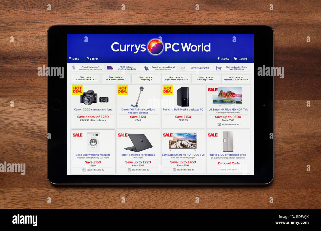 Il sito web di Currys mondo PC è visto su un tablet iPad, il quale è appoggiato su un tavolo di legno (solo uso editoriale). Foto Stock