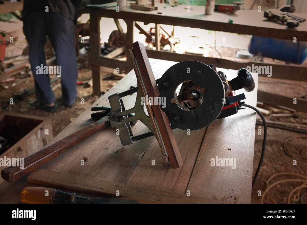 Attrezzatura sulla scrivania in legno con uomo che lavora in background in officina Foto Stock