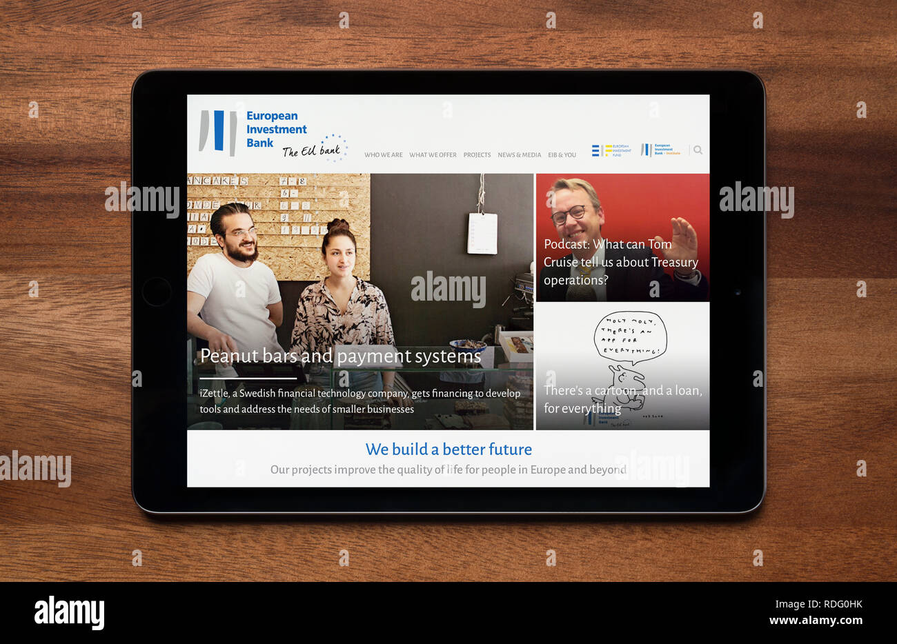 Il sito web della Banca europea per gli investimenti è visto su un tablet iPad, il quale è appoggiato su un tavolo di legno (solo uso editoriale). Foto Stock