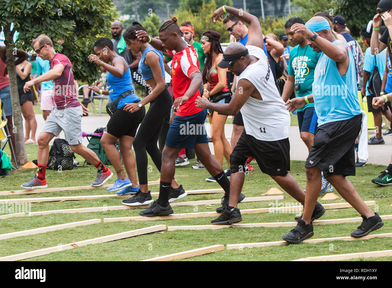 Adulto concorrenti cercano di mantenere il loro equilibrio mentre rapidamente camminando su strette tavole di legno in un gioco ad Atlanta di giorno del Campo di Atlanta, GA. Foto Stock