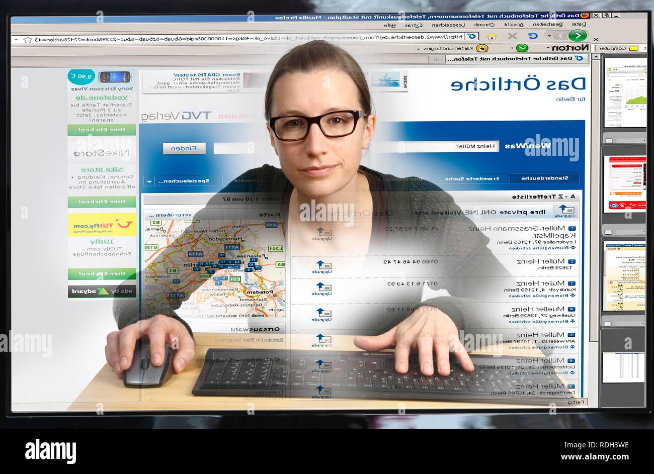 Giovane donna seduta a un computer per navigare in Internet, la visualizzazione di una pagina per la ricerca di numeri di telefono, Das Oertliche Foto Stock