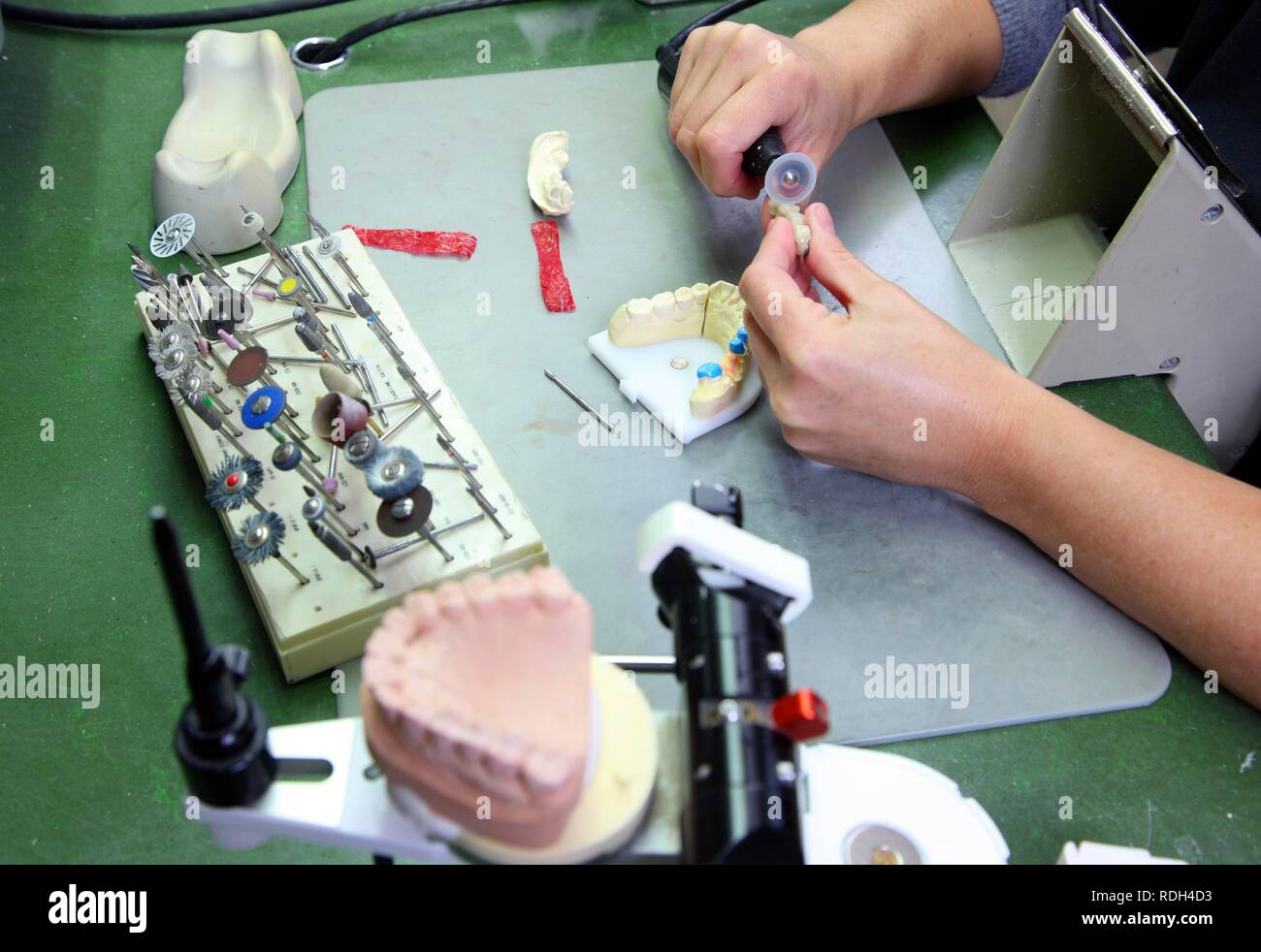 Laboratorio dentale, la fabbricazione di una protesi dentale da un maestro artigiano, macinazione e separazione di una ceramica dentale impiallacciato Foto Stock