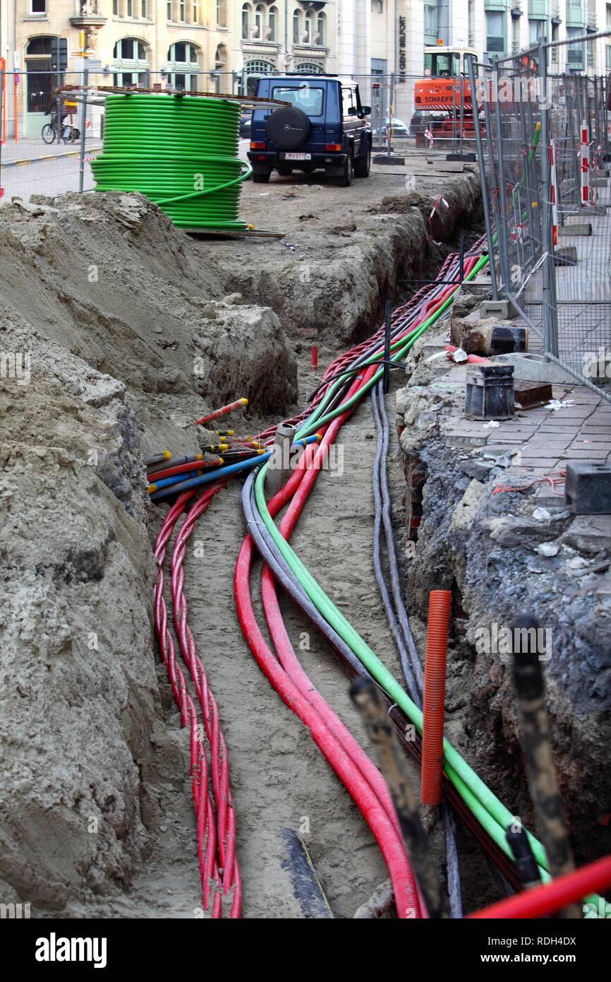 Installazione di vari cavi in un cantiere edile, linee di alimentazione e i cavi di telecomunicazione, alcuni in tubi di protezione Foto Stock