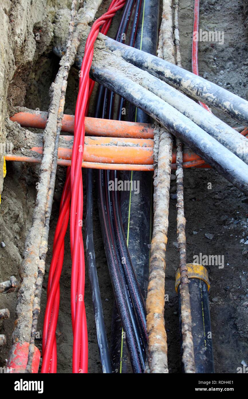 Installazione di vari cavi in un cantiere edile, linee di alimentazione e i cavi di telecomunicazione, alcuni in tubi di protezione Foto Stock