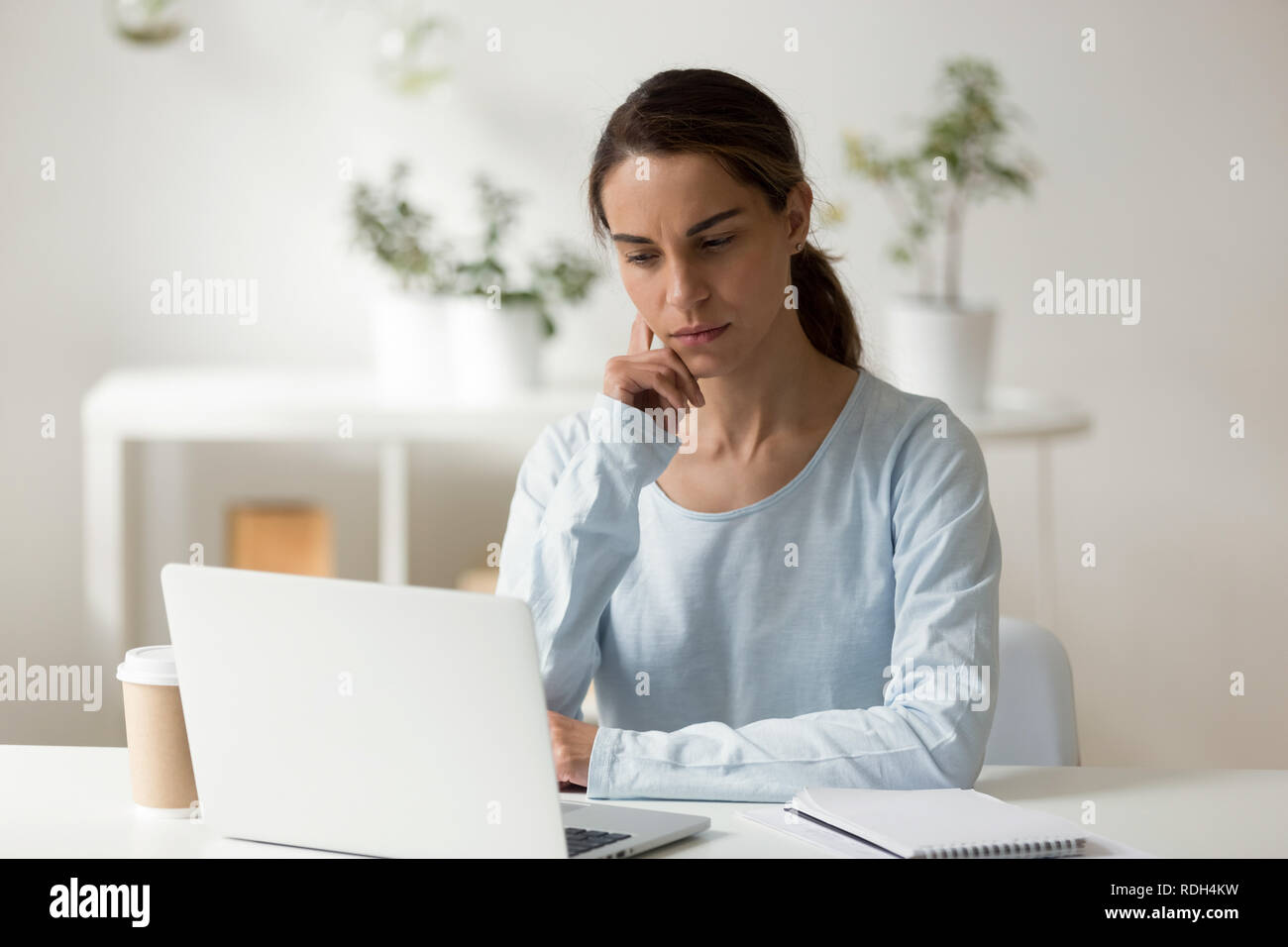 Femmina serio studente utilizzando laptop, lavorando sul progetto difficile Foto Stock