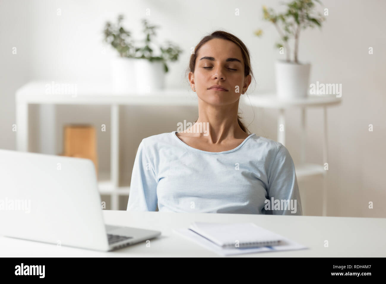Calma e attraente donna di relax presso il luogo di lavoro con gli occhi chiusi Foto Stock